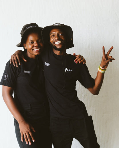 Two people wearing black The Litterboom T Shirts with visible branding against a white background